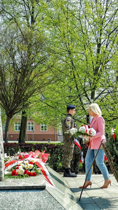 osoba z kwiatami przed pomnikiem